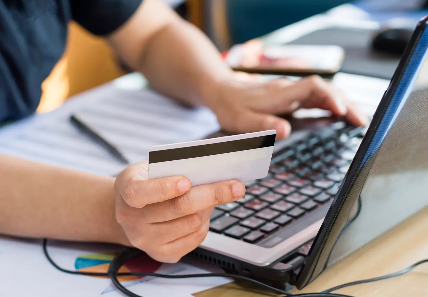 A man using a laptop and holding a card.